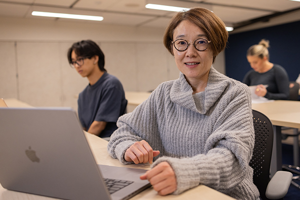 An adult student using a laptop in a classroom